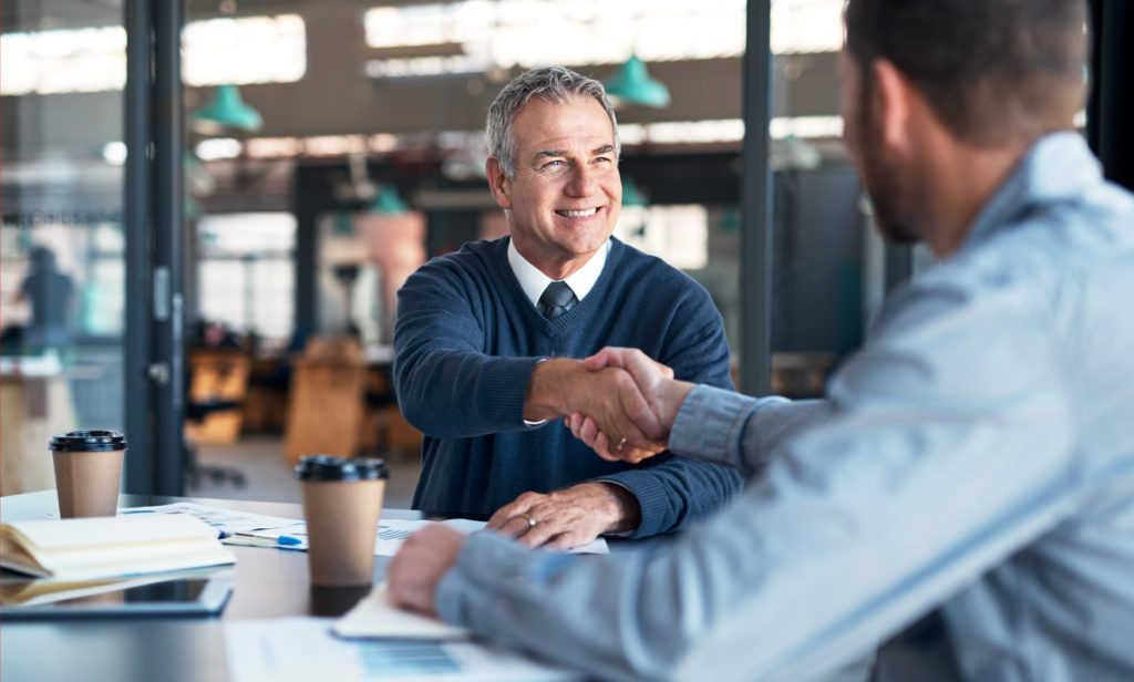 Unternehmensnachfolge: Vater und Sohn sitzen im Meetingzimmer und besprechen die Nachfolge.